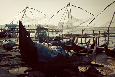 Boats moored by fishing nets at beach against clear sky