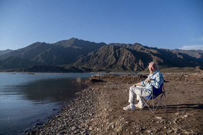 Man sitting in a camping chair while relaxing outdoors in nature.