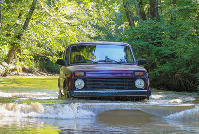 The russian crossover wades through the river. the car drives along the river