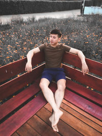 High angle view of young man sitting on bench against plants
