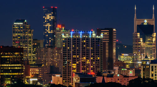 Illuminated buildings in city against sky at night