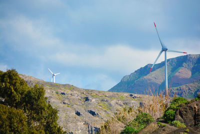 Wind turbines on mountain against sky