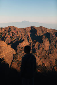 Rear view of man looking at mountain against sky