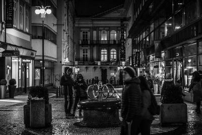 People walking on illuminated street at night