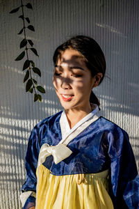 Young woman wearing traditional clothing while standing against wall