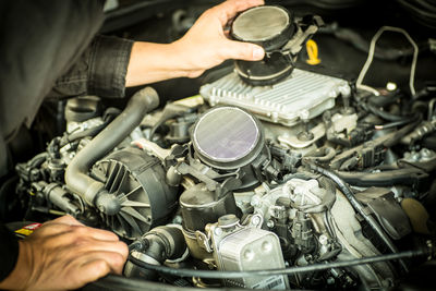 Midsection of man repairing car engine