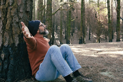 Side view of woman sitting on tree trunk