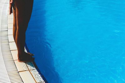 Low section of woman standing in swimming pool