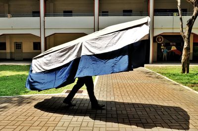 Man carrying fabric material against built structure