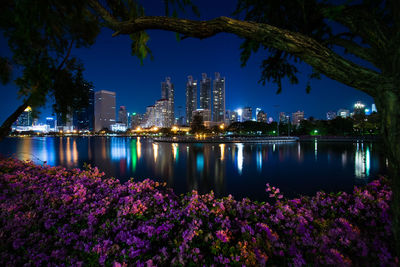 Illuminated city by river at night