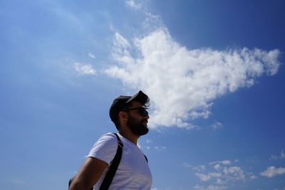 Low angle view of young man looking away against sky