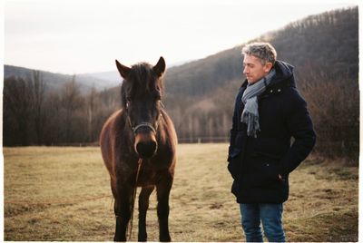 Man standing with horse on field