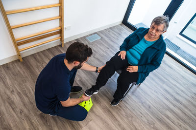 Senior lady during exercise with trainer using equipment in gym