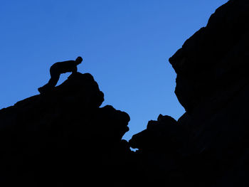 Low angle view of silhouette rocks on mountain against clear sky