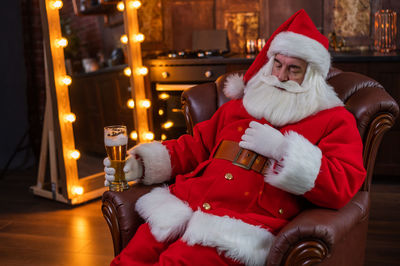 Santa clause holding beer glass resting at home