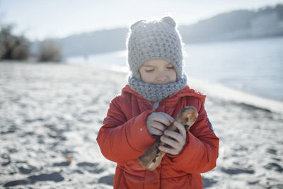 Cute girl wearing warm clothing standing on snow covered field during winter