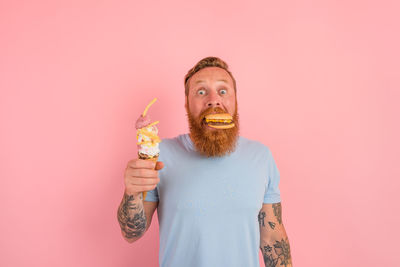 Midsection of man holding ice cream against red background