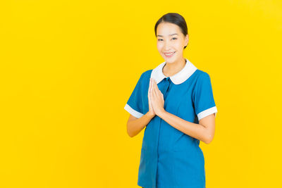 Portrait of a smiling young woman against yellow background