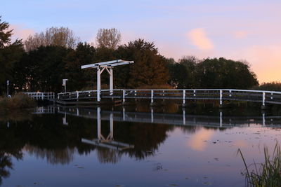 Reflection of silhouette trees in water against sky