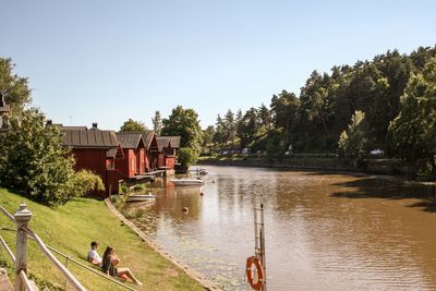 People by river against clear sky