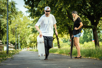 Couple with skateboards on footpath at park