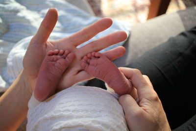 Midsection of mother holding baby feet