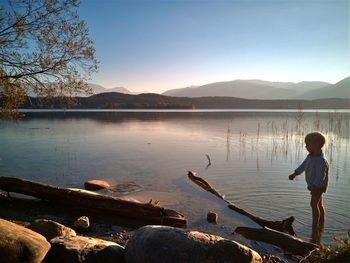 Boy standing on lake against sky