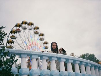 Low angle view of woman and ferris wheel against clear sky