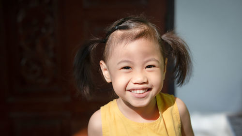Positive charming 4 years old cute baby asian girl, little child with adorable pigtails hair smiling