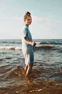 Girl showing okay gesture standing in a water spending a free time over a sea during summer vacation