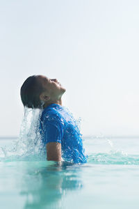 Portrait of boy swimming in pool against sea