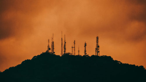 Low angle view of silhouette communications tower against sky during sunset