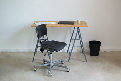Empty chair by laptop on desk in office