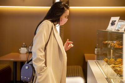 Side view of woman wearing mask looking at retail display