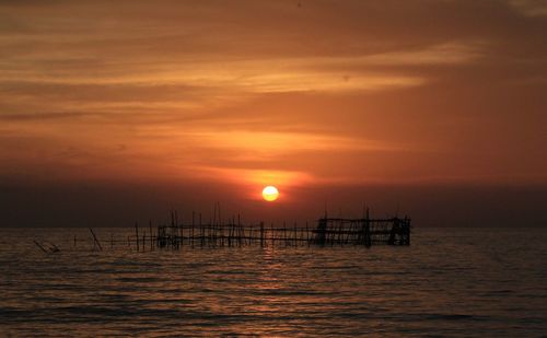 Silhouette of boat in sea during sunset