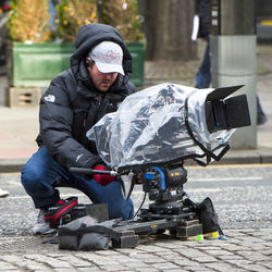 Man holding umbrella on footpath in city