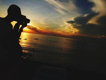 Silhouette man on beach against sky during sunset