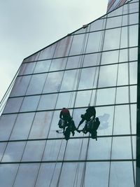 Low angle view of men working against sky