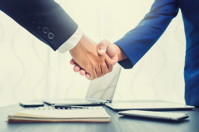 Cropped image of businessmen shaking hands at table