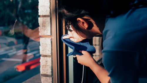 Young woman looking through window