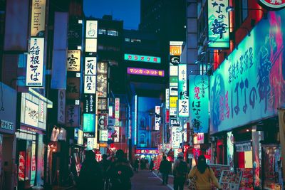 People walking on illuminated city street at night