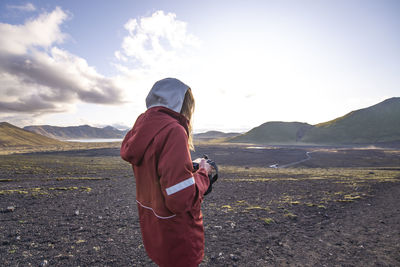 Young woman looking down at camera in front of the sunset, highlands