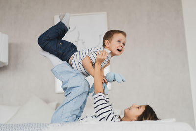 Side view of cute siblings playing on bed at home