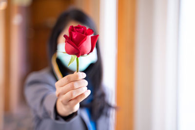 Close-up of woman holding red flower