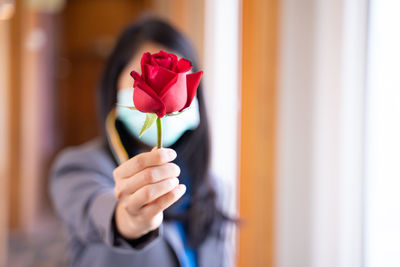 Close-up of woman holding red flower