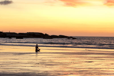 Silhouette person on beach against sky during sunset