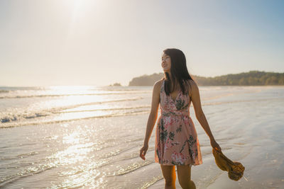 Woman standing at beach against sky