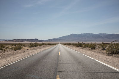 Road leading towards mountain against sky