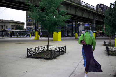 Rear view of man walking on sidewalk in city