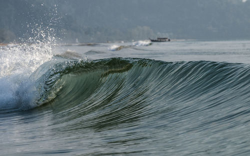 Sea waves splashing on shore with boat